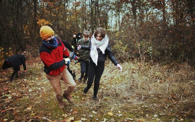Members of the Wagabunda Scouts troop haul a fallen tree out of the the Jewish cemetery of Nowe Miasto, Poland, November 11, 2020. (Julia Bandurska/ via JTA)