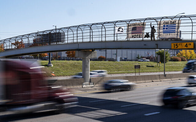 An Iraq and Afghanistan war veteran, who did not give his name, stands on a highway overpass with signs encouraging motorists to vote in Hamtramck, Michigan, October 28, 2020. (AP Photo/David Goldman) An Iraq and Afghanistan war veteran, who did not give his name, stands on a highway overpass with signs encouraging motorists to vote in Hamtramck, Michigan, October 28, 2020. (AP Photo/David Goldman)