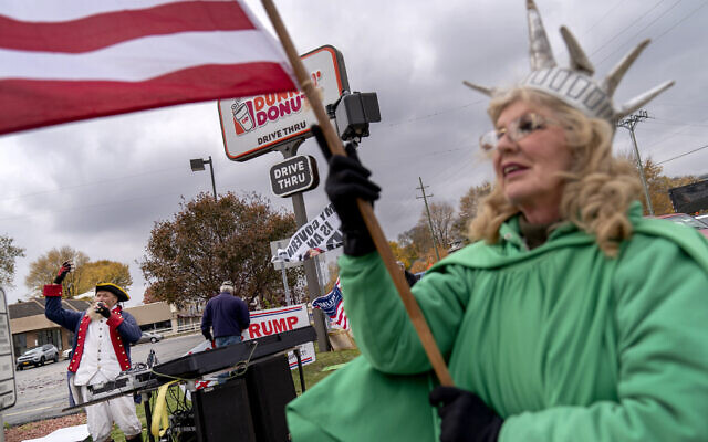 Trump supporters Carol Reed, dressed as the Statue of Liberty, right, and Matthew Woods, dressed as a Continental Army soldier, cheer at an intersection during a rally in Mount Clemens, Michigan, October 29, 2020. (AP Photo/David Goldman) Trump supporters Carol Reed, dressed as the Statue of Liberty, right, and Matthew Woods, dressed as a Continental Army soldier, cheer at an intersection during a rally in Mount Clemens, Michigan, October 29, 2020. (AP Photo/David Goldman)
