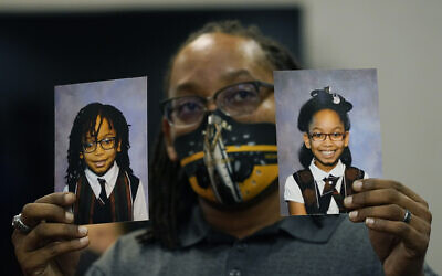 In this Tuesday, Oct. 27, 2020 photo, Sheldon Smith, center, holds the photographs of his children Deshawn Smith, 11, left, and Trinitee Smith, 13, both suffering from sickle cell anemia, during an Initiative 65 rally in Ridgeland, Miss. Smith and his wife Keishawna Smith believe their children would benefit from medical marijuana treatment for pain management. Initiative 65 would amend the Mississippi Constitution to allow the prescription by a doctor of up to 5 ounces (142 grams) of marijuana per month for people who suffer from one of more than 20 medical conditions.  (AP Photo/Rogelio V. Solis)