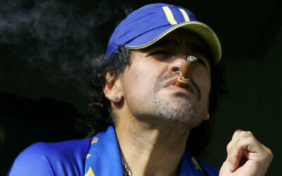 In this March 26, 2006, photo, former soccer player Diego Maradona smokes a cigar as he watches Argentina's first division soccer match between Boca Juniors and River Plate in Buenos Aires, Argentina. (AP Photo/Natacha Pisarenko, File)