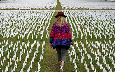 In this Oct. 27, 2020, Artist Suzanne Brennan Firstenberg walks among thousands of white flags planted in remembrance of Americans who have died of COVID-19 near Robert F. Kennedy Memorial Stadium in Washington. Regardless of the presidential election outcome, a vexing issue remains to be decided: Will the US be able to tame a perilous pandemic that is surging as holidays, winter and other challenges approach? Public health experts fear the answer is no, at least in the short term, with potentially dire consequences. (AP Photo/Patrick Semansky, File)