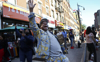 Marcel Cothron sings "Na na na na, hey hey goodbye" with a large crowd gathered on Fulton Street in the Brooklyn borough of New York, to celebrate Joe Biden's victory over President Donald Trump, Saturday, Nov. 7, 2020. (AP Photo/Jessie Wardarski)
