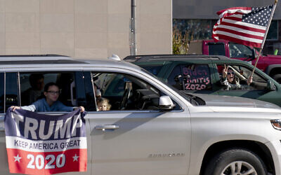 A Biden supporter at right, cheers, while driving past a Trump rally protesting the election results after Joe Biden was declared the winner Saturday, Nov. 7, 2020, at the State Capitol in Lansing, Michigan  (AP Photo/David Goldman)