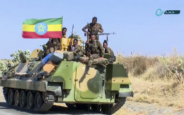 Screen capture from undated video released by the state-owned Ethiopian News Agency on November 16, 2020 shows Ethiopian military personnel sitting on an armored personnel carrier next to a national flag, on a road in an area near the border of the Tigray and Amhara regions of Ethiopia. (Ethiopian News Agency via AP) Screen capture from undated video released by the state-owned Ethiopian News Agency on November 16, 2020 shows Ethiopian military personnel sitting on an armored personnel carrier next to a national flag, on a road in an area near the border of the Tigray and Amhara regions of Ethiopia. (Ethiopian News Agency via AP)