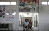 In this Sunday, Oct. 7, 2018 photo, Syrian soldiers who lost their legs while fighting in Syria's war, wheel past a poster showing Syrian President Bashar Assad, after a physical therapy session at the Ahmad Hamish Martyr hospital, in Damascus, Syria. (AP/Hassan Ammar)
