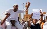 A man holds a poster with Arabic that reads, 'We will not give up, we will not sell out, we will not agree on normalization,' as others chant slogans to protest Sudanese President of the Sovereignty Council Abdel Fattah Abdelrahman Burhan's contentious decision to meet Prime Minister Benjamin Netanyahu in a move toward normalizing relations, in Khartoum, Sudan, Feb. 7, 2020. (AP Photo/Marwan Ali)