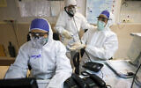 Illustrative: A medic disinfects the hands of colleague against the coronavirus, at a hospital in Tehran, Iran, March 1, 2020 (Koosha Mahshid Falahi/Mizan News Agency via AP)