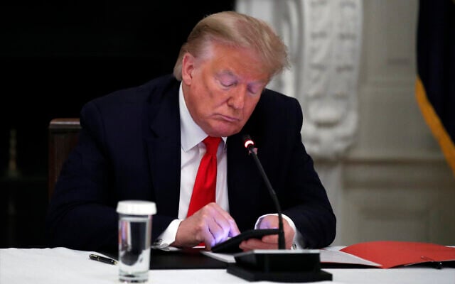 US President Donald Trump looks at his phone during a roundtable with governors on the reopening of America's small businesses, in the State Dining Room of the White House, June 18, 2020, in Washington. (AP Photo/Alex Brandon) US President Donald Trump looks at his phone during a roundtable with governors on the reopening of America's small businesses, in the State Dining Room of the White House, June 18, 2020, in Washington. (AP Photo/Alex Brandon)
