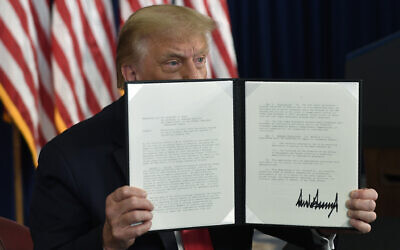 US President Donald Trump signs an executive order during a news conference at the Trump National Golf Club in Bedminster, N.J., Saturday, Aug. 8, 2020. (AP/Susan Walsh)