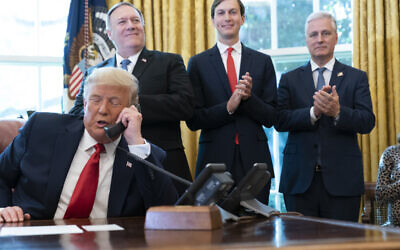 US President Donald Trump talks on the phone with the leaders of Sudan and Israel, as Secretary of State Mike Pompeo, left, White House senior adviser Jared Kushner, and National Security Adviser Robert O'Brien, applaud in the Oval Office, October 23, 2020. (AP Photo/Alex Brandon)
