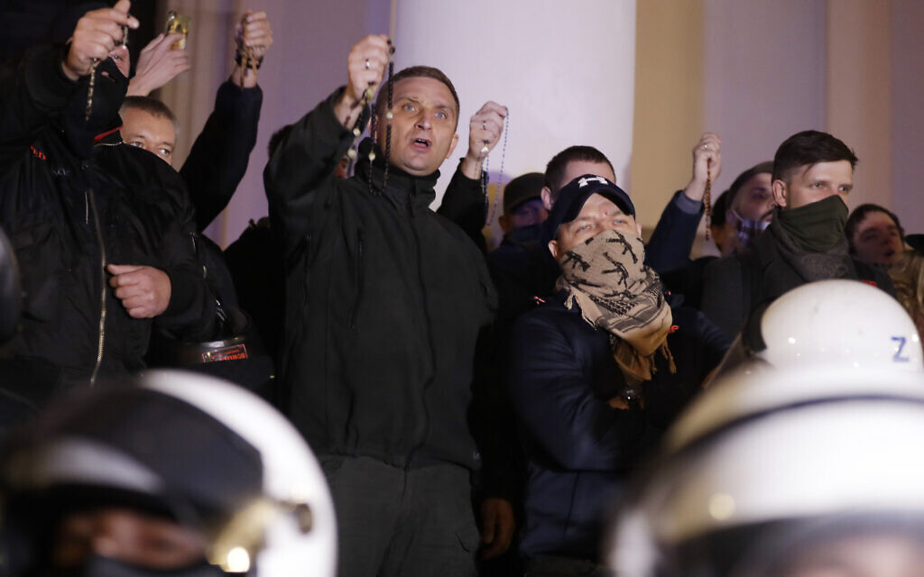 Far-right activists with rosaries sing a religious song as they block entry to a church against hundreds of women's activists and their supporters protesting for the fifth day against a court ruling tightening Poland's strict abortion law, in Warsaw, Poland, on Monday, October 26, 2020. (AP Photo/Czarek Sokolowski)