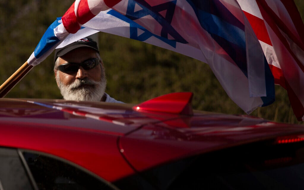 An Israeli supporter of the re-election of US President Donald Trump waves American and Israeli flags from a car at a rally outside of the US Embassy, in Jerusalem, Tuesday, Oct. 27, 2020. (AP Photo/Maya Alleruzzo)