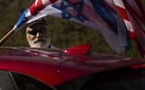An Israeli supporter of the re-election of US President Donald Trump waves American and Israeli flags from a car at a rally outside of the US Embassy, in Jerusalem, Tuesday, Oct. 27, 2020. (AP Photo/Maya Alleruzzo)
