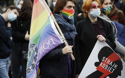 Women's rights activists protest against recent tightening of Poland's restrictive abortion law in front of the parliament building as inside, guards had to be used to shield right-wing ruling party leader Jaroslaw Kaczynski from angry opposition lawmakers, in Warsaw, Poland, on Tuesday, October 27, 2020. (AP Photo/Czarek Sokolowski)
