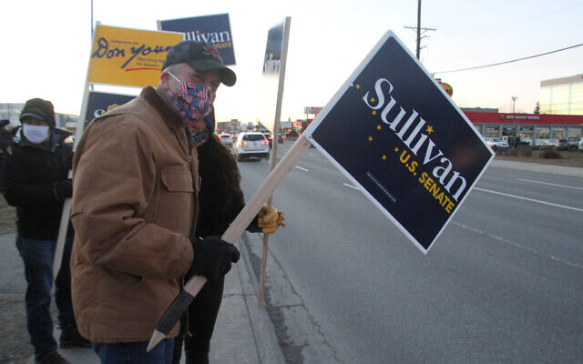 US Sen. Dan Sullivan, an Alaska Republican seeking reelection, waves a sign at a busy intersection on November 2, 2020, in Anchorage, Alaska. (AP Photo/Mark Thiessen) US Sen. Dan Sullivan, an Alaska Republican seeking reelection, waves a sign at a busy intersection on November 2, 2020, in Anchorage, Alaska. (AP Photo/Mark Thiessen)