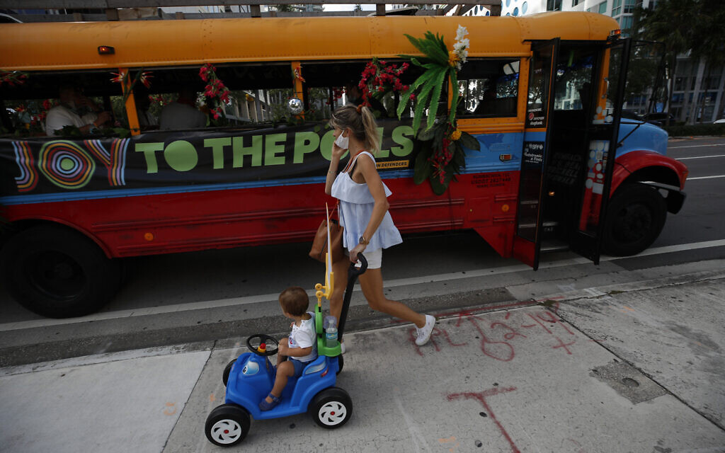 Pedestrians pass by a bus, where "Joy to the Polls" volunteers were playing music to liven up a polling station in downtown Miami, on Election Day, Tuesday, Nov. 3, 2020.(AP/Rebecca Blackwell)