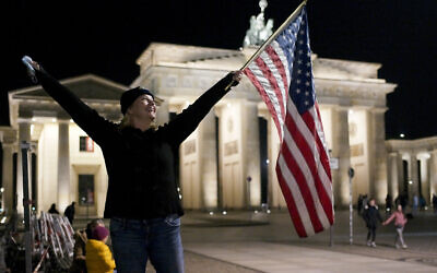 Marianne Hoenow from Connecticut in the US celebrates the victory of President-elect Joe Biden and Vice President-elect Kamala Harris in front of the Brandenbug Gate next to the United States embassy in Berlin, Germany, Saturday, Nov. 7, 2020. (AP/Markus Schreiber)