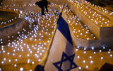 A man turns on LED candles at a memorial for Israel's victims of COVID-19, in Jerusalem, November 8, 2020. (AP Photo/ Oded Balilty)