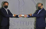 Sao Paulo Governor Joao Doria, left, and Butantan Institute Director Dimas Covas hold up a box of an experimental COVID-19 vaccine that is being tested in partnership with China's pharmaceutical company Sinovac during a press conference in Sao Paulo, Brazil, November 9, 2020. (AP Photo/Andre Penner)
