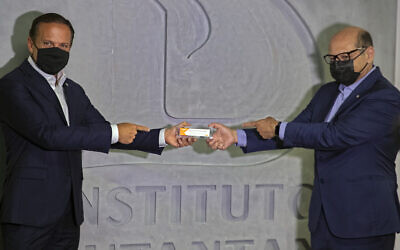 Sao Paulo Governor Joao Doria, left, and Butantan Institute Director Dimas Covas hold up a box of an experimental COVID-19 vaccine that is being tested in partnership with China's pharmaceutical company Sinovac during a press conference in Sao Paulo, Brazil, November 9, 2020. (AP Photo/Andre Penner)