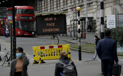 A sign is displayed outside Waterloo train station to remind people thy are required to wear face coverings inside the station and whilst travelling on trains during England's second coronavirus lockdown, in London, Friday, Nov. 20, 2020.  Britain yesterday registered 501 daily COVID-19 deaths within 28 days of a positive test and is the fifth country in the world to record more than 50,000 coronavirus-related deaths. (AP Photo/Matt Dunham)