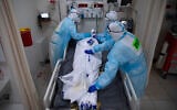 Medical personnel wearing protective equipment cover the body of a man who died from COVID-19, in the intensive care ward for coronavirus patients at Shaare Zedek Medical Center in Jerusalem, November 23, 2020. (AP Photo/Oded Balilty)