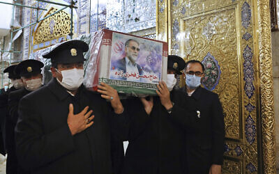 In this picture released by the Iranian Defense Ministry and taken on Saturday, Nov. 28, 2020, caretakers from the Imam Reza holy shrine, carry the flag draped coffin of Mohsen Fakhrizadeh, an Iranian scientist linked to the country's disbanded military nuclear program, who was killed on Friday, during a funeral ceremony in the northeastern city of Mashhad, Iran.  (Iranian Defense Ministry via AP)