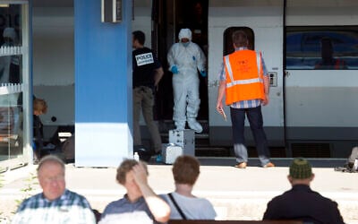 People wait for a train in the foreground as members of a police forensics team take part in an investigation next to a Thalys train on the platform at Arras train station, northern France, August 22, 2015. (Virginia Mayo/AP)