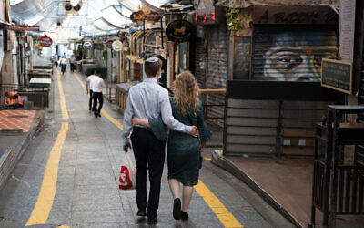 Illustrative: A couple walks in Jerusalem's Mahane Yehuda market on September 25, 2020, during a nationwide lockdown to prevent the spread of COVID-19. (Nati Shohat/Flash90)
