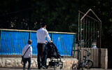 An ultra-Orthodox boy walks with his father to a Talmud Torah school in the Sanhedrin neighborhood in Jerusalem, October 18, 2020. (Yonatan Sindel/Flash90)