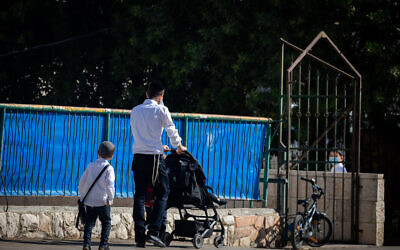 An ultra-Orthodox boy walks with his father to a Talmud Torah school in the Sanhedrin neighborhood in Jerusalem, October 18, 2020. (Yonatan Sindel/Flash90)