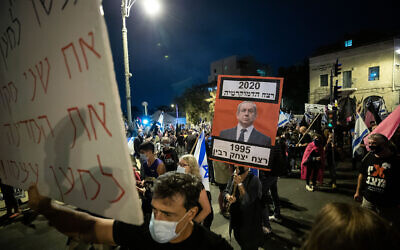 A protester holds up a sign of Netanyahu, alongside the caption: "1995: The murder of Yitzhak Rabin. 2020: the murder of democracy" in Jerusalem, on October 31, 2020. (Yonatan Sindel/Flash90)