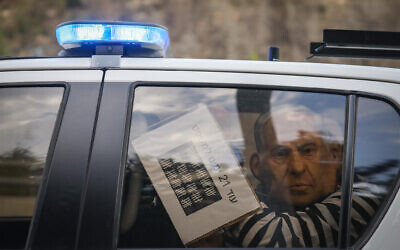 A protester wearing a mask depicting Prime Minister Benjamin Netanyahu and wearing a prisoner's uniform is detained during a demonstration on November 14, 2020 (Yonatan Sindel/Flash90)