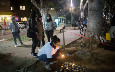 A woman light candles in memory of women murdered in domestic violence, at a street memorial on Rothschild Boulevard, Tel Aviv, ahead of International Day of Violence Against Women. November 24, 2020. (Miriam Alster/FLASH90)