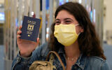 An Israeli passenger from a flydubai flight from Tel Aviv waves her Israeli passport on arrival at Dubai International Airport in the United Arab Emirates, November 26, 2020. (AP Photo/Jon Gambrell)