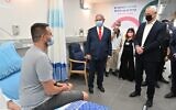 Prime Minister Benjamin Netanyahu (C) and Defense Minister Benny Gantz (R) speak with Segev Harel, the first volunteer for trials for an experimental Israeli coronavirus vaccine, at Sheba Medical Center, November 1, 2020. (Ariel Hermoni/Defense Ministry)