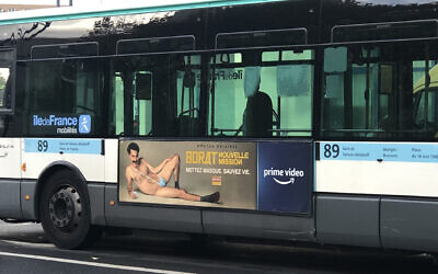 A RATP bus with a billboard of Sacha Baron Cohen wearing a ring with the word "Allah" on it moves through Paris, France on November 2, 2020. (Courtesy of @firehairedreamr/Twitter via JTA)