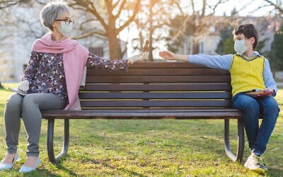Illustrative: A grandmother passes chocolate to her grandson while keeping distance to reduce COVID-19 risk (kzenon via iStock by Getty Images)