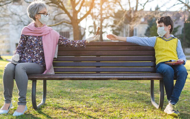 Illustrative: A grandmother passes chocolate to her grandson while keeping distance to reduce COVID-19 risk (kzenon via iStock by Getty Images)