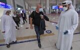 An Israeli man walks past Emirati staff after passport control upon arrival from Tel Aviv to the Dubai airport in the United Arab Emirates, on November 26, 2020. (Karim Sahib/AFP)