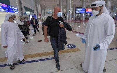 An Israeli man walks past Emirati staff after passport control upon arrival from Tel Aviv to the Dubai airport in the United Arab Emirates, on November 26, 2020. (Karim Sahib/AFP) An Israeli man walks past Emirati staff after passport control upon arrival from Tel Aviv to the Dubai airport in the United Arab Emirates, on November 26, 2020. (Karim Sahib/AFP)
