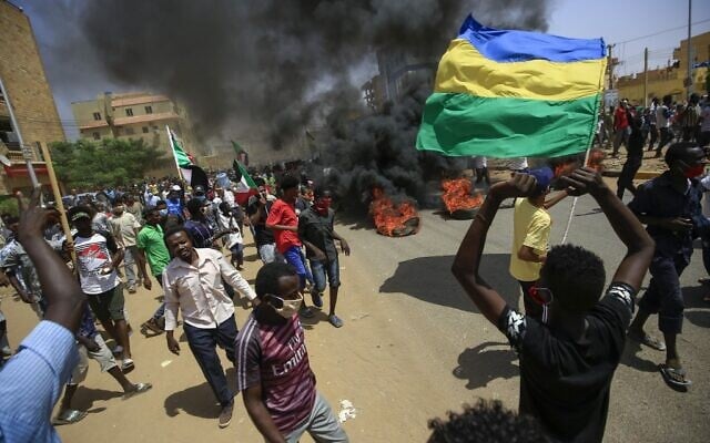 Sudanese demonstrators wave Sudan's independence-era flag (R) as smoke billows from burning tyres during a protest in Khartoum, June 30, 2020. (ASHRAF SHAZLY / AFP) Sudanese demonstrators wave Sudan's independence-era flag (R) as smoke billows from burning tyres during a protest in Khartoum, June 30, 2020. (ASHRAF SHAZLY / AFP)