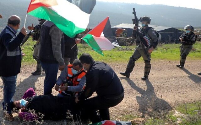 Palestinian men assist an injured protester amid clashes with Israeli security forces following a demonstration against the expansion of settlements in the town of Salfit, in the West Bank, on December 4, 2020. (JAAFAR ASHTIYEH/AFP) Palestinian men assist an injured protester amid clashes with Israeli security forces following a demonstration against the expansion of settlements in the town of Salfit, in the West Bank, on December 4, 2020. (JAAFAR ASHTIYEH/AFP)