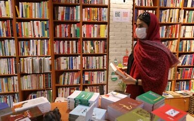 A woman picks a book at a bookstore on Enqelab (Revolution) street in Iran's capital Tehran, on September 8, 2020. (ATTA KENARE/AFP)