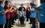 Margaret Keenan (C) is applauded by staff as she returns to her ward after becoming the first person in the United Kingdom to receive the Pfizer-BioNtech COVID-19 vaccine at University Hospital in Coventry, England, on December 8, 2020. (Jacob King/Pool/AFP)