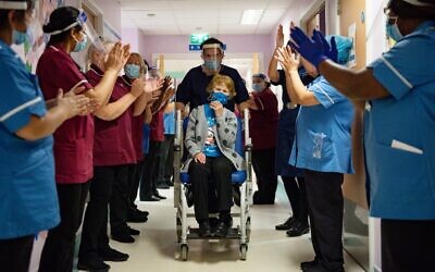 Margaret Keenan (C) is applauded by staff as she returns to her ward after becoming the first person in the United Kingdom to receive the Pfizer-BioNtech COVID-19 vaccine at University Hospital in Coventry, England, on December 8, 2020. (Jacob King/Pool/AFP)
