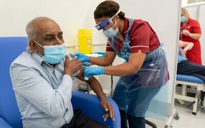 Care home worker Pillay Jagambrun (L), 61, reacts as he receives a dose of the Pfizer/BioNTech COVID-19 vaccine at Croydon University Hospital in south London on December 8, 2020. (Dan CHARITY / POOL / AFP)