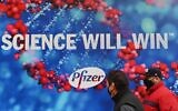 People wearing protective face masks walk past the Pfizer Inc. headquarters on December 9, 2020 in New York City. (Angela Weiss / AFP)