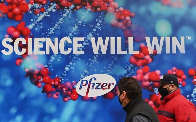 People wearing protective face masks walk past the Pfizer Inc. headquarters on December 9, 2020 in New York City. (Angela Weiss / AFP) People wearing protective face masks walk past the Pfizer Inc. headquarters on December 9, 2020 in New York City. (Angela Weiss / AFP)